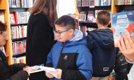 Die Schülerinnen und Schüler schauen die Bücher in den Bücherregalen durch und zeigen sich gegenseitig gefundene Bücher.