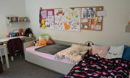 Man sieht das Zimmer einer Schülerin mit ihrem Bett, einem Schreibtisch und viel Dekoration