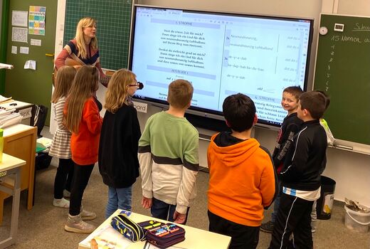 Die Lehrerin spielt Gitarre und die Schüler und Schülerinnen singen