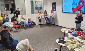 Jugendliche hören einer Lehrerin zu, die etwas auf dem interaktiven Panel präsentiert