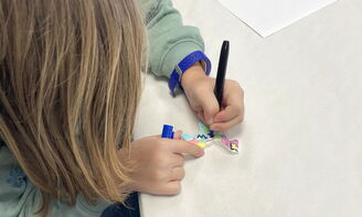 Ein Mädchen bemalt einen Lama-Christbaumanhänger