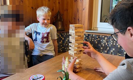 Drei Schüler spielen das Spiel Wackelturm und haben Spaß.