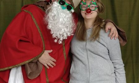 Eine Schülerin steht neben dem Nikolaus. Sie hat eine lustige Brille und ein Hirschgeweih auf.