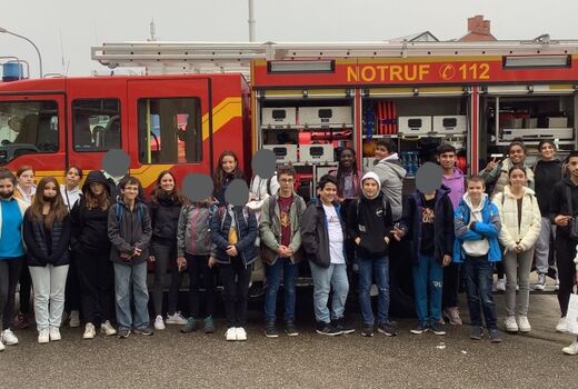 Vierundzwanzig SchülerInnen und drei Lehrerinnen stehen vor einem Feuerwehrwagen und lachen in die Kamera.
