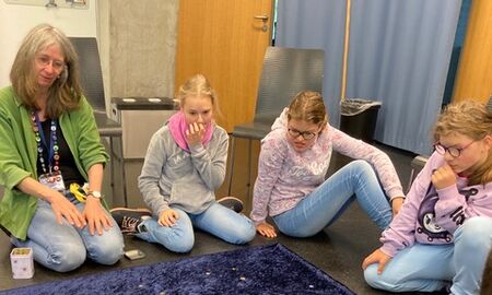 Kinder legen auf einer dunkelblauen Decke Sternbilder
