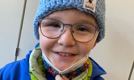 Ein Schüler mit Maske und einer selbstgehäkelten Mütze auf dem Kopf