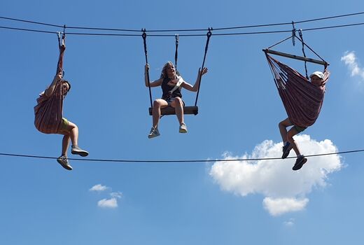 Drei Schülerinnen hängen in Hängematten in luftiger Höhe