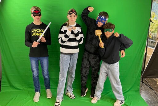 Schülerinnen und Schüler stehen verkleidet vor dem Greenscreen