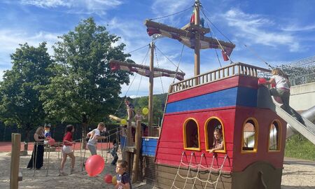 Kinder spielen an einem Piratenschiff im Sandkasten
