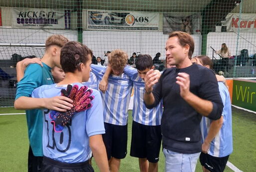 Die Schüler stehen im Kreis. Der Trainer erklärt.