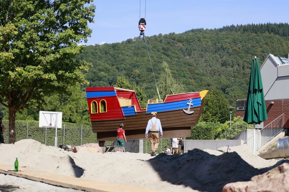 Zwei Handwerker und das Playmobil-Schiff auf dem Weg zum endgültigen Stellplatz.