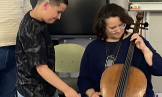 Ein Junge streicht mit dem Bogen über das Cello