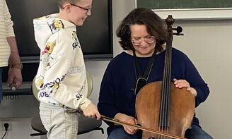 Ein Junge streicht mit dem Bogen über das Cello