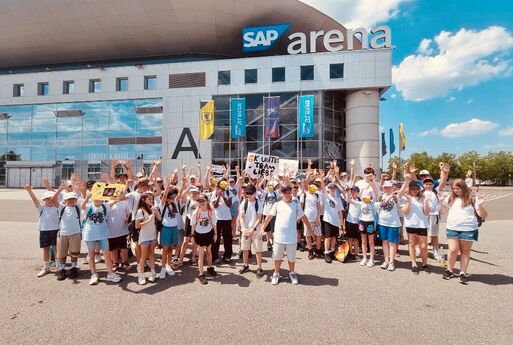 SchülerInnen und LehrerInnen stehen vor der SAP Arena und freuen sich