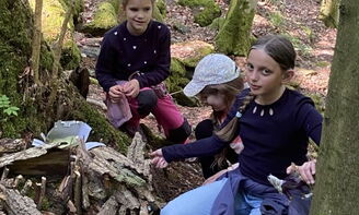 Drei Mädchen bauen ein Haus aus Rinde im Wald