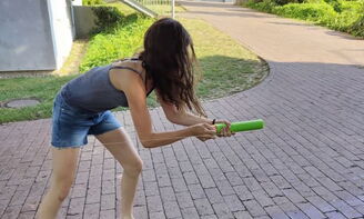 Eine Jugendliche schießt mit einer Wasserpistole einen Becher an einer Schnur entlang