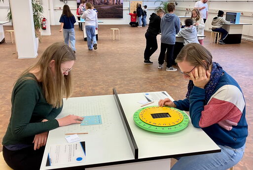 Zwei Lehrerinnen sitzen sich an einem Tisch gegenüber und lösen verschiedene Aufgaben zur Geheimschrift