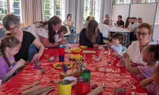 Erwachsene basteln mit Kleinkindern am Tisch