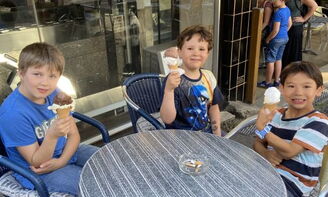 Kinder sitzen Eisessend im Eiscafe