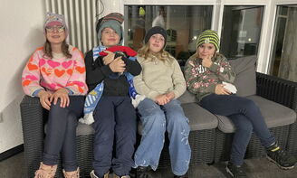 Vier Jugendliche präsentieren ihre winterliche Kopfbedeckungen