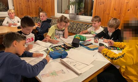 Acht Schüler sitzen an zwei Tischen und schreiben ihr Tagebuch über die Erlebnisse im Schullandheim.