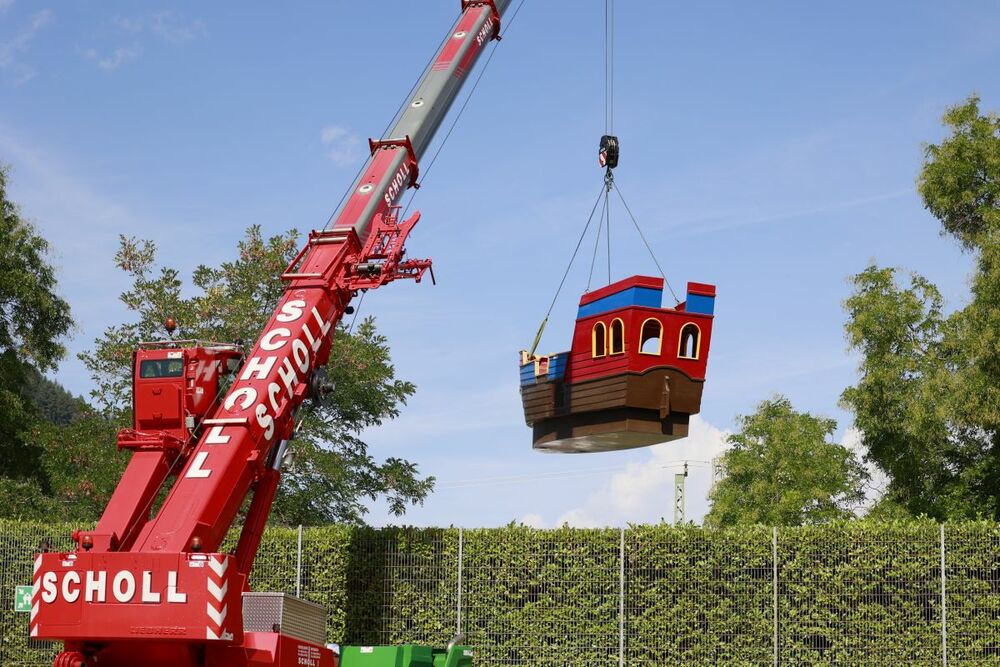 Das Playmobil-Schiff wird mit einem Kran über die Hecke gehoben.