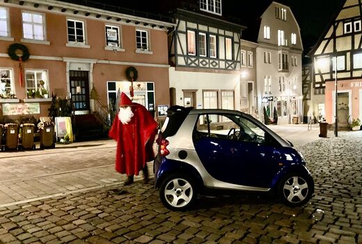 Der Nikolaus steigt aus seinem Auto aus. Es sind Häuser und der Marktplatz in Neckargemünd zu sehen.