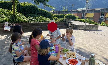 Sechs Kinder stecken an einem Biertisch Gemüsestücke auf Spieße