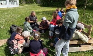 Eine Lehrerin liest einer Gruppe von Kindern im Freien eine Trollgeschichte vor