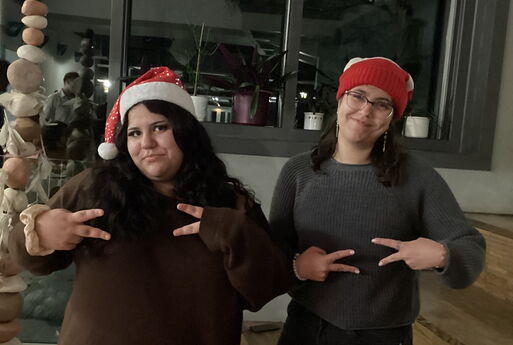 Zwei Schülerinnen mit Weihnachtsmütze posieren vor der Kamera