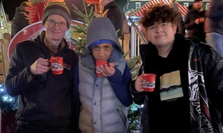 Zwei Jungen und ein Lehrer trinken Kinderpunsch auf dem Weihnachtsmarkt