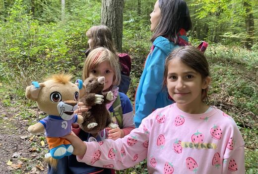 Leo und Mauli, unsere Freitagsclubmaskottchen, sind bei jedem Abenteuer mit dabei. Zwei Mädchen halten die Plüschtiere in die Kamera.