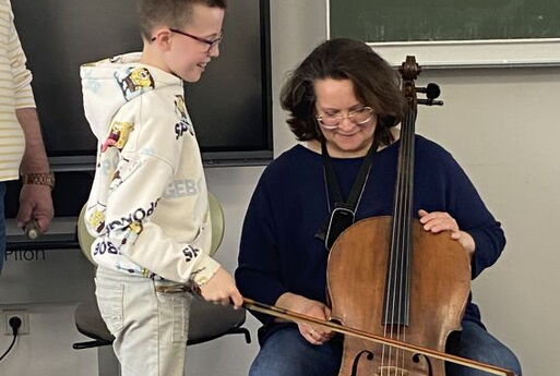 Ein Junge streicht mit dem Bogen über das Cello