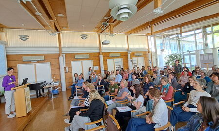 Die Referentin steht am Rednerpult vor einem sitzenden Publikum