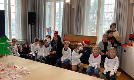 Kinder mit weißen Hemden warten auf einer Bank sitzend auf ihren Auftritt