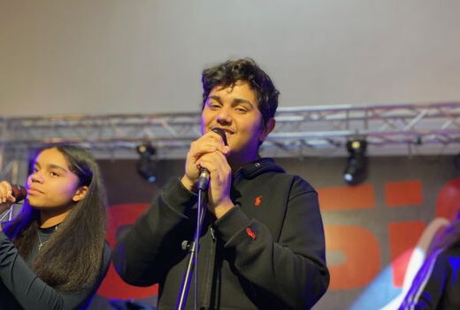 Zwei SchülerInnen am Mikrofon. Der vordere Schüler singt und lächelt.