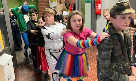 Schüler und Schülerinnen machen eine Polonaise durch die geschmückte Verwaltung und laufen hintereinander durch eine offene Tür.