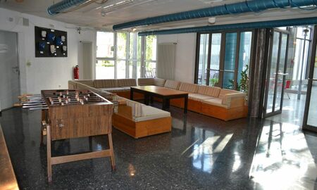 Man sieht einen Aufenthaltsraum für ältere Schüler mit einem Tischkicker und einer Sitzgruppe mit Tisch