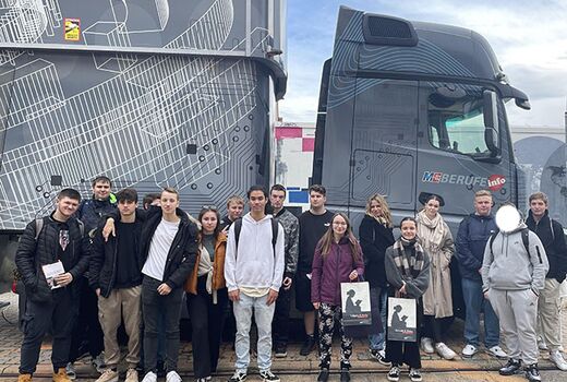 Eine Gruppe von Schülerinnen und Schülern der Beruflichen Bildung positionieren sich für ein Gruppenbild vor einem LKW der Messe.