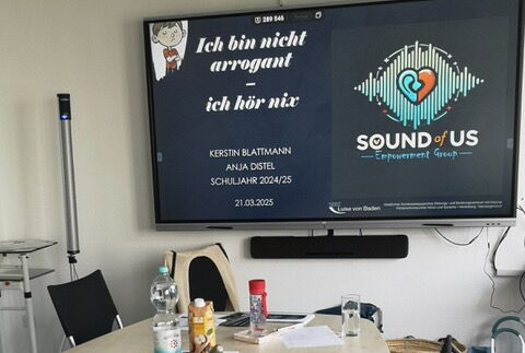 Ein Arbeitszimmer mit Panel auf dem Steht "sound of us" Ich bin nicht arrogant-ich hör nix!"
