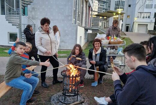 SchülerInnen und ErzieherInnen die Stockbrot über dem Feuer garen.