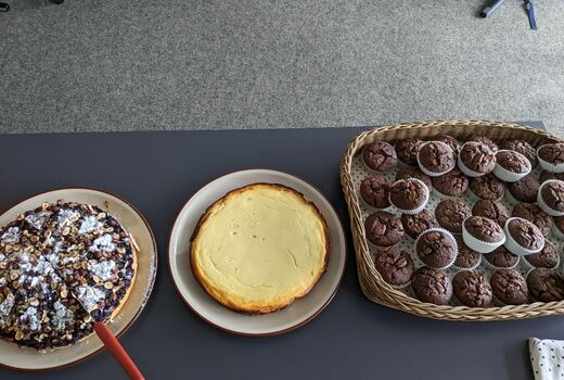 Auf einem Tisch stehen zwei ganze Kuchen und ein Tablett mit Mussins.