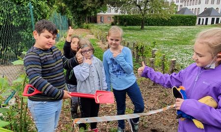 Fünf Schüler stehen um einen Komposthaufen und strecken den Daumen nach oben.