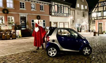 Der Nikolaus steigt aus seinem Auto aus. Es sind Häuser und der Marktplatz in Neckargemünd zu sehen.