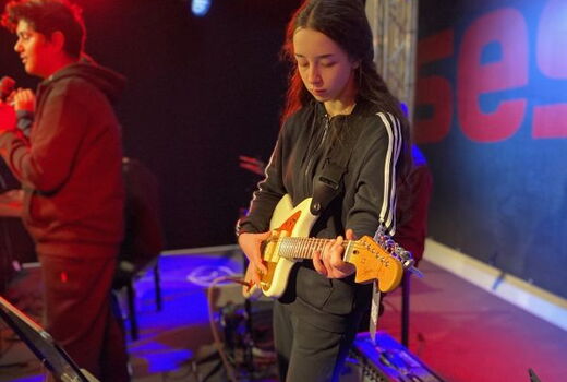 Eine Schülerin spielt konzentriert E-Gitarre