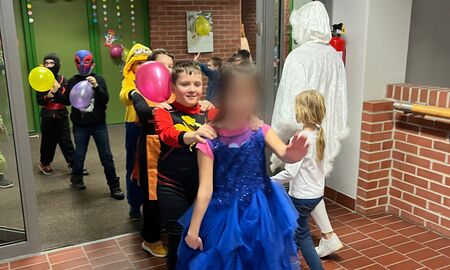 Schüler und Schülerinnen machen eine Polonaise durch die geschmückte Verwaltung und laufen hintereinander durch eine offene Tür.