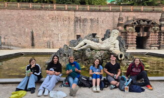 Die Gruppe sitzt vor dem Brunnen.