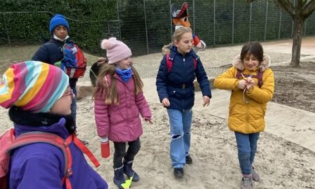 Fünf Kinder stehen in einem Sandkasten