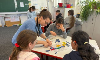Eine Lehrerin unterstützt die Schüler beim Schließen des Stromkreislaufes