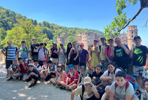 Ein Gruppenfoto von Kindern, im Hintergrund ist Wald und ein Teil des Schlosses von Heidelberg zu sehen